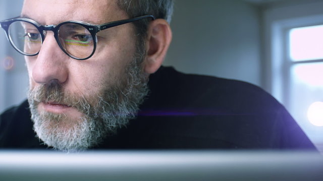 Mature Businessman with glasses working at home office - close up tracking shot 