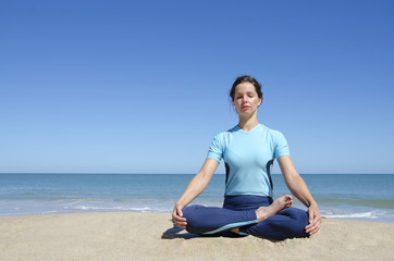 Fototapeta na wymiar Girl in cross-legged yoga lotus pose at beach
