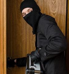 Male burglar stealing case with money