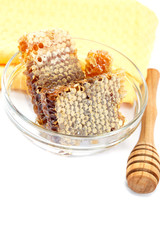 Honey comb in a glass bowl and wooden stick, isolated on white b
