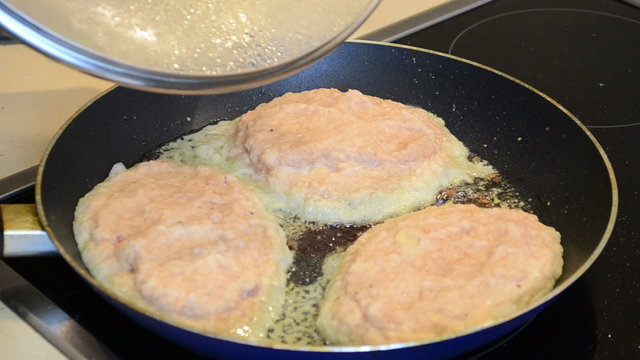 baking potatoes pancakes with meat. hand open pan cover
