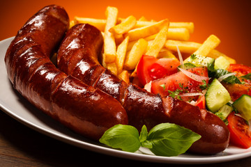 Grilled sausages, French fries and vegetables