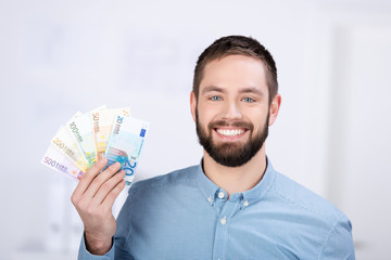 lächelnder mann hält geldscheine in der hand