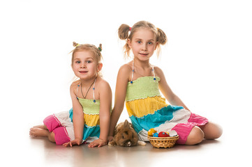 Two little girls playing with Easter bunny on a white background
