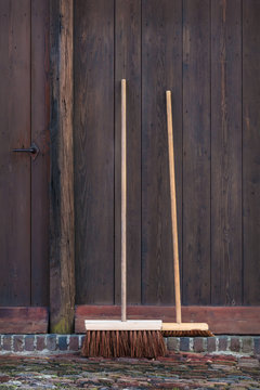 Two brooms in front of an old barn