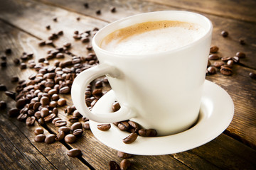 Cup of coffee and beans on wooden table.