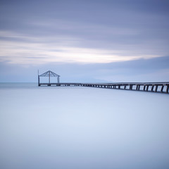 Wooden pier or jetty silhouette and blue ocean on sunset