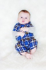 The five-months baby lies on a fur plaid