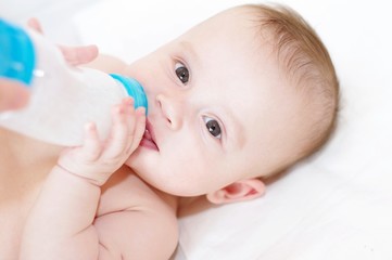 The five-months baby eats from a small bottle