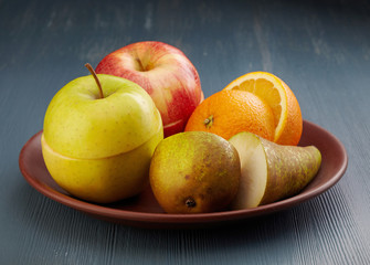 various chopped fruits plate on dark painted wooden table