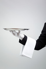 Waiter holding empty silver tray over gray background