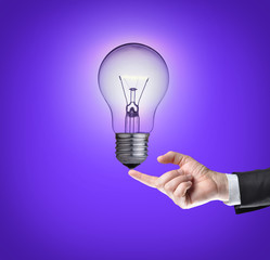Light bulb on tip of finger on businessman.Purple background.
