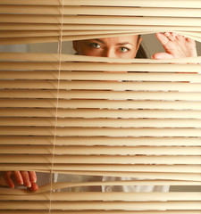 Portrait of a woman looking through out the blinds