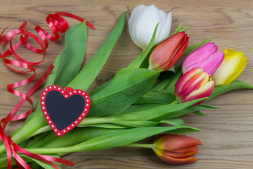 Tulpenstrauß auf Holz mit Geschenkband und Herz