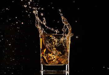  Glass of whiskey with splash, isolated on black background