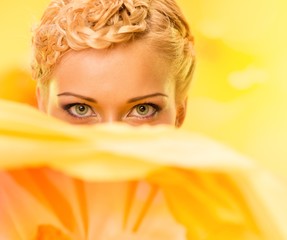 Beautiful young woman hiding behind big yellow flower