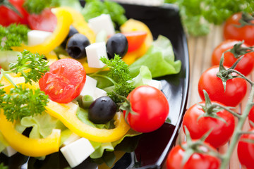 Obraz na płótnie Canvas salad with fresh vegetables on a black plate