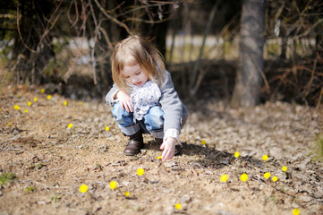 Little toddler girl touching spring flowers