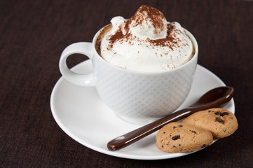 tazza di cappuccino con panna, cacao e due biscotti