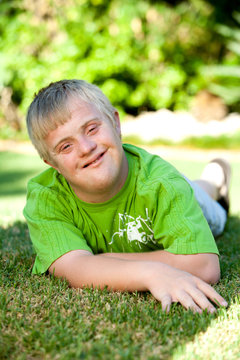 Portrait of handicapped boy on green grass.