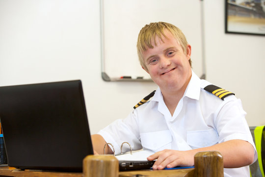 Portrait of young pilot with down syndrome at desk.