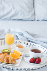 Fototapeta na wymiar Tray with tasty breakfast on a bed