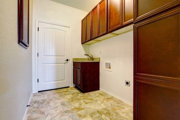 New empty laundry room with wood cabinets.