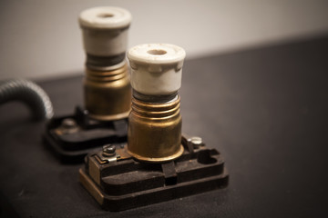 Two vintage electrical fuses on dark panel