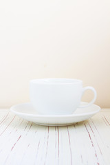 Fototapeta na wymiar Coffee cup on white wooden table over bright background