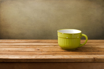 Empty green cup on wooden table over grunge background