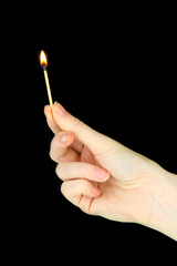 Burning match in female hand, isolated on black