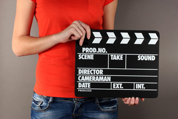 Movie production clapper board in hands on grey background