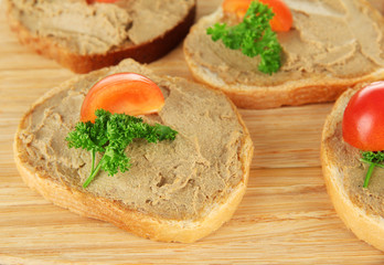 Fresh pate on bread on wooden board, close up