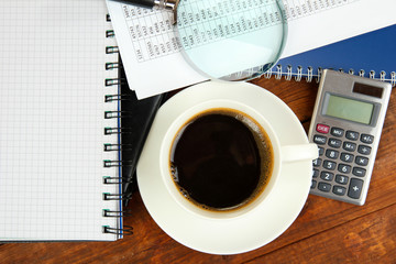Cup of coffee on worktable covered with documents close up