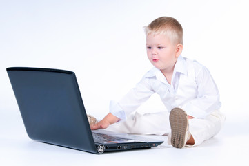 Little business boy in  solid white suit sitting at notebook on