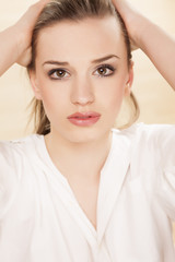 depressed young woman posing with her ​​hands in her hair...