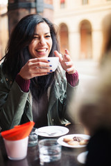 Young woman drinking coffee in a cafe outdoors. 