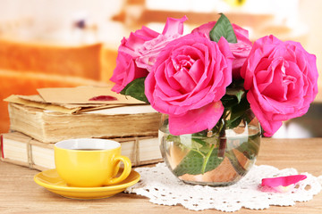 Beautiful pink roses in vase on wooden table on room background