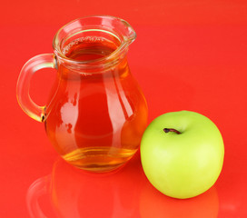 Full jug of apple juice and apple on color background