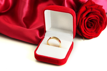 Beautiful box with wedding ring and rose on red silk background