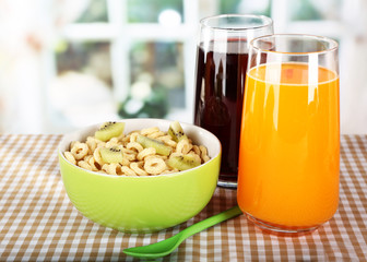 Delicious and healthy cereal in bowl with juice on table in