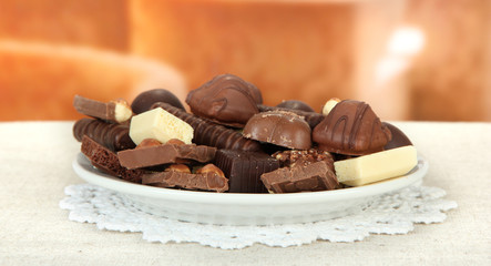 Chocolate and sweets on white plate, on bright background