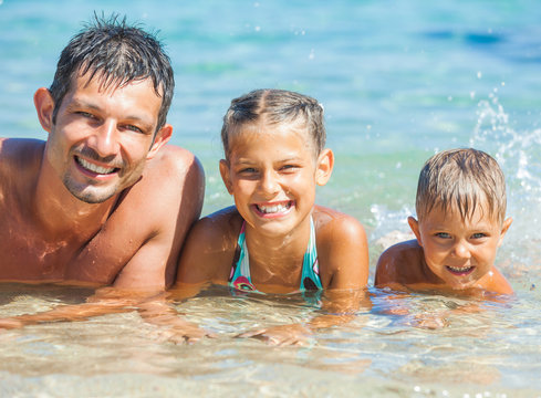 Father with his kids have fun and swim sea