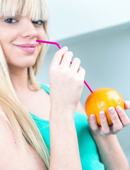 charming girl drinking an orange from a straw