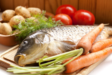 Fresh fish on a wooden board with vegetables