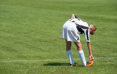 Obraz premium young football player doing stretching exercises