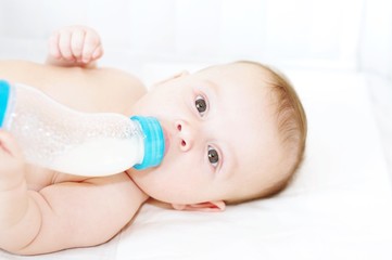 The five-months baby eats from a small bottle himself