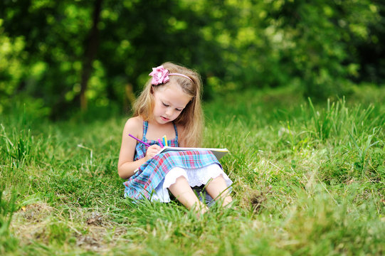 Sweet Little Girl Drawing In A Park