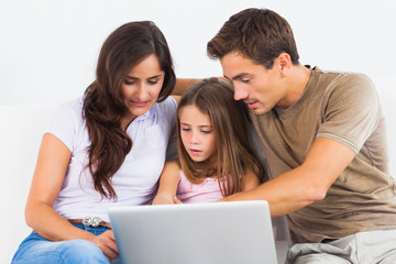 Fototapeta na wymiar Rodzina siedzi na kanapie z laptopem