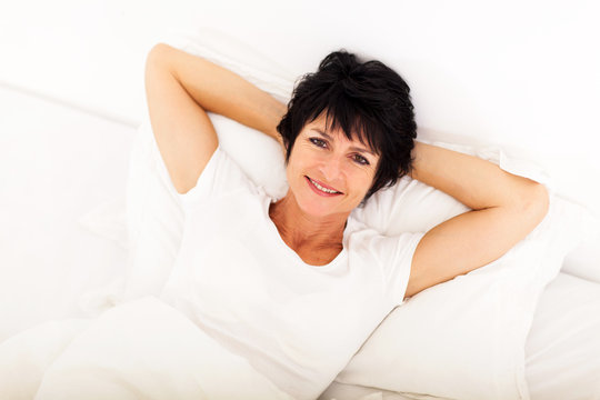 Above View Of Happy Middle Aged Woman Lying On Bed